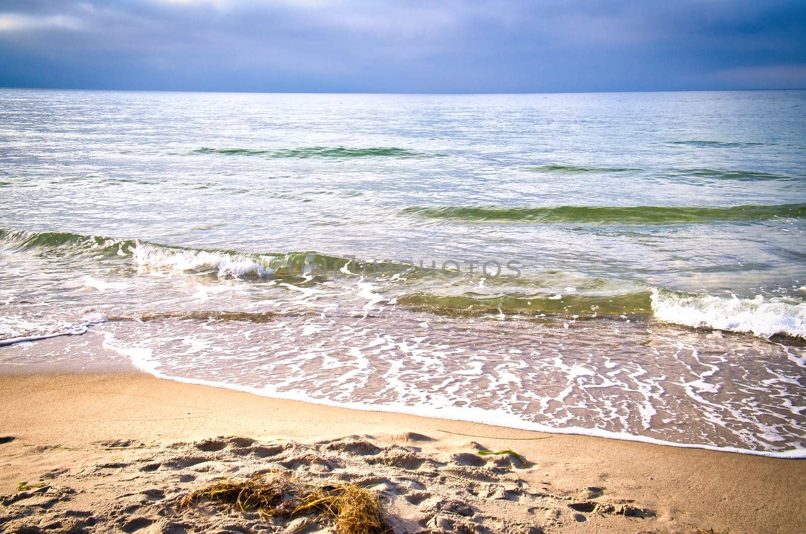On the coast of the Baltic Sea. Waves roll onto the sandy beach. Nature photo by the sea