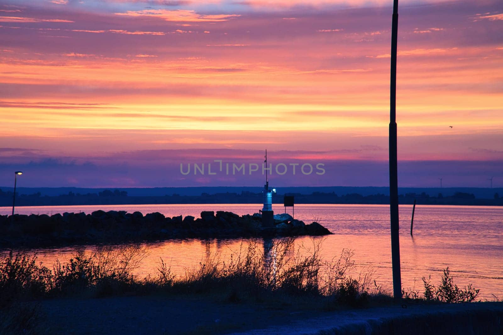 Sunset in Sweden at the harbor of lake Vaettern. Lighthouse in the background at dusk. Landscape shot in Scandinavia.