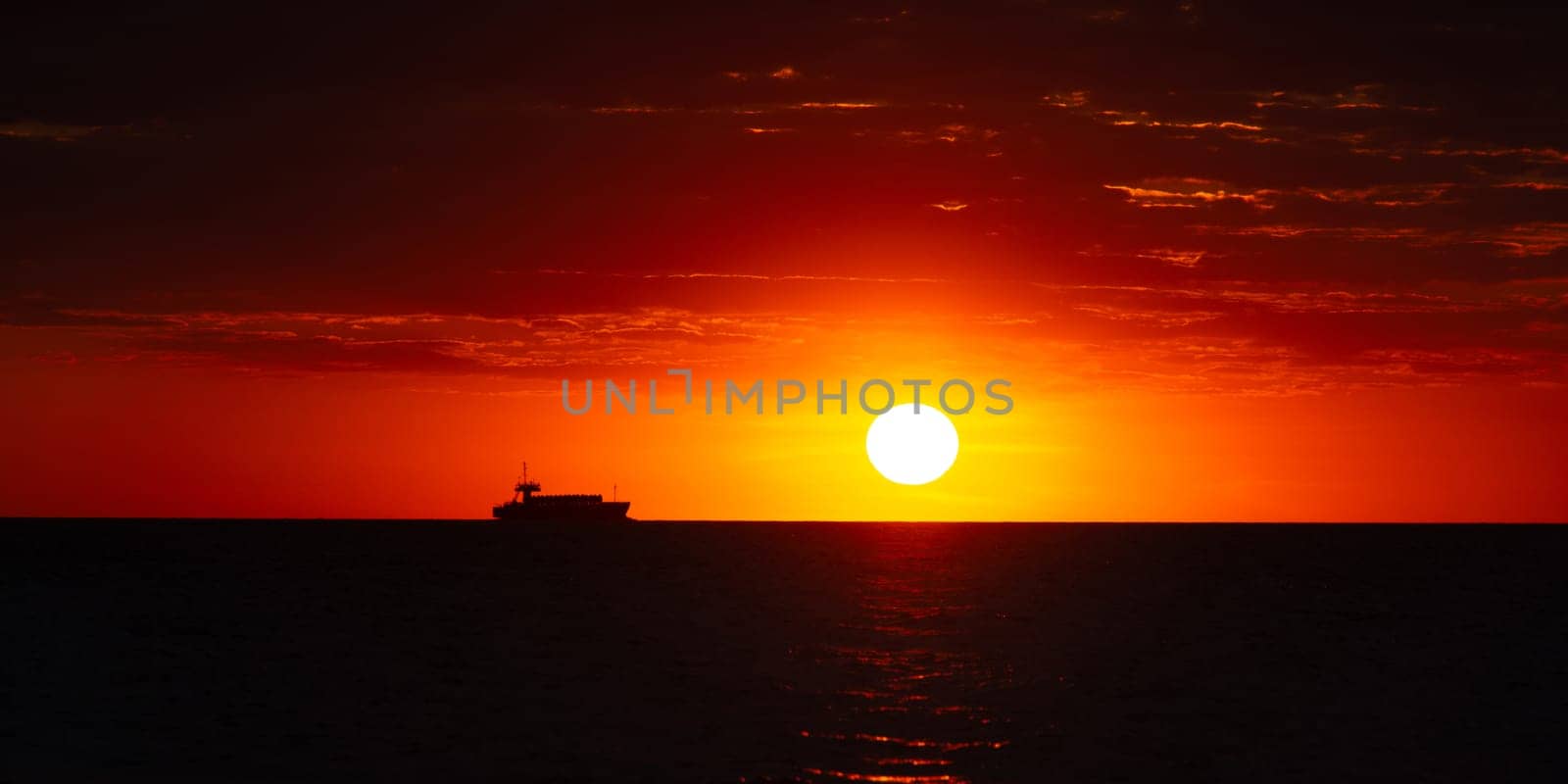 Beautiful orange sunset over the sea, a ship on the horizon