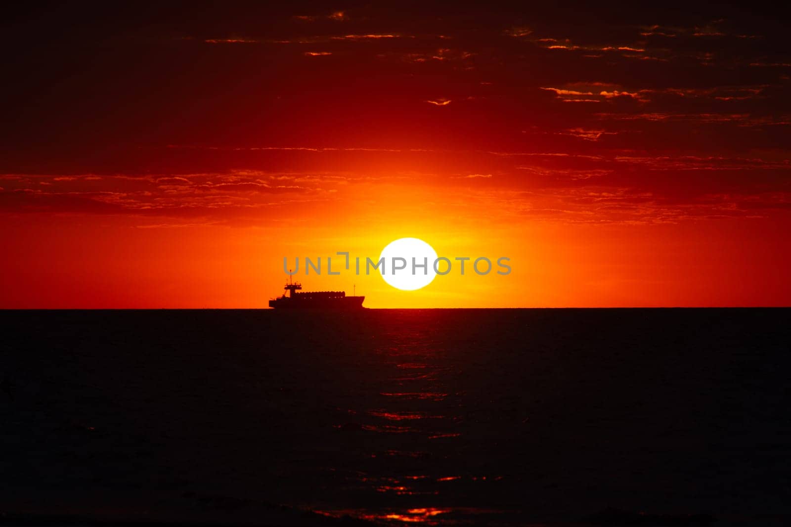 Beautiful orange sunset over the sea, a ship on the horizon