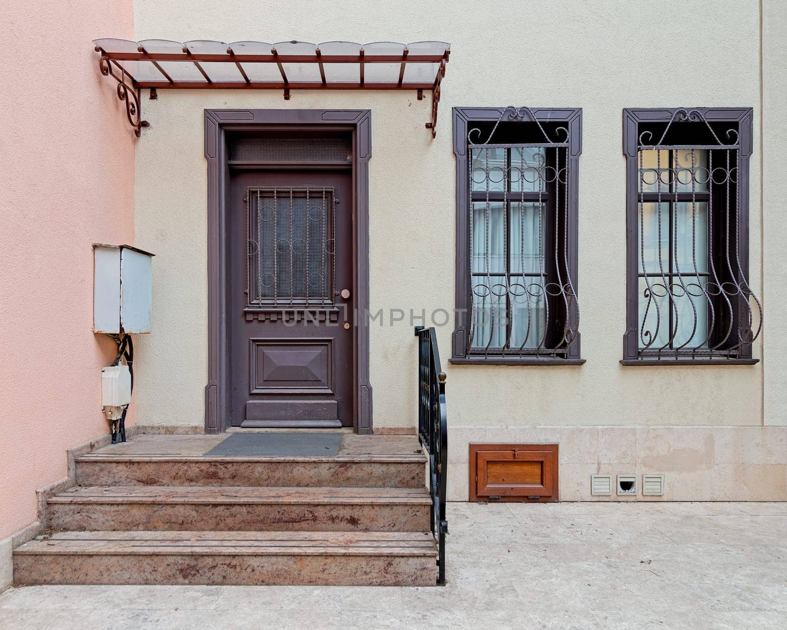 Brightly painted doorway with wooden decorated door, decorated wrought iron windows, and welcoming stairs leading to a cozy home at Istanbul's vibrant Kuzguncuk neighborhood, Uskudar district, Turkey