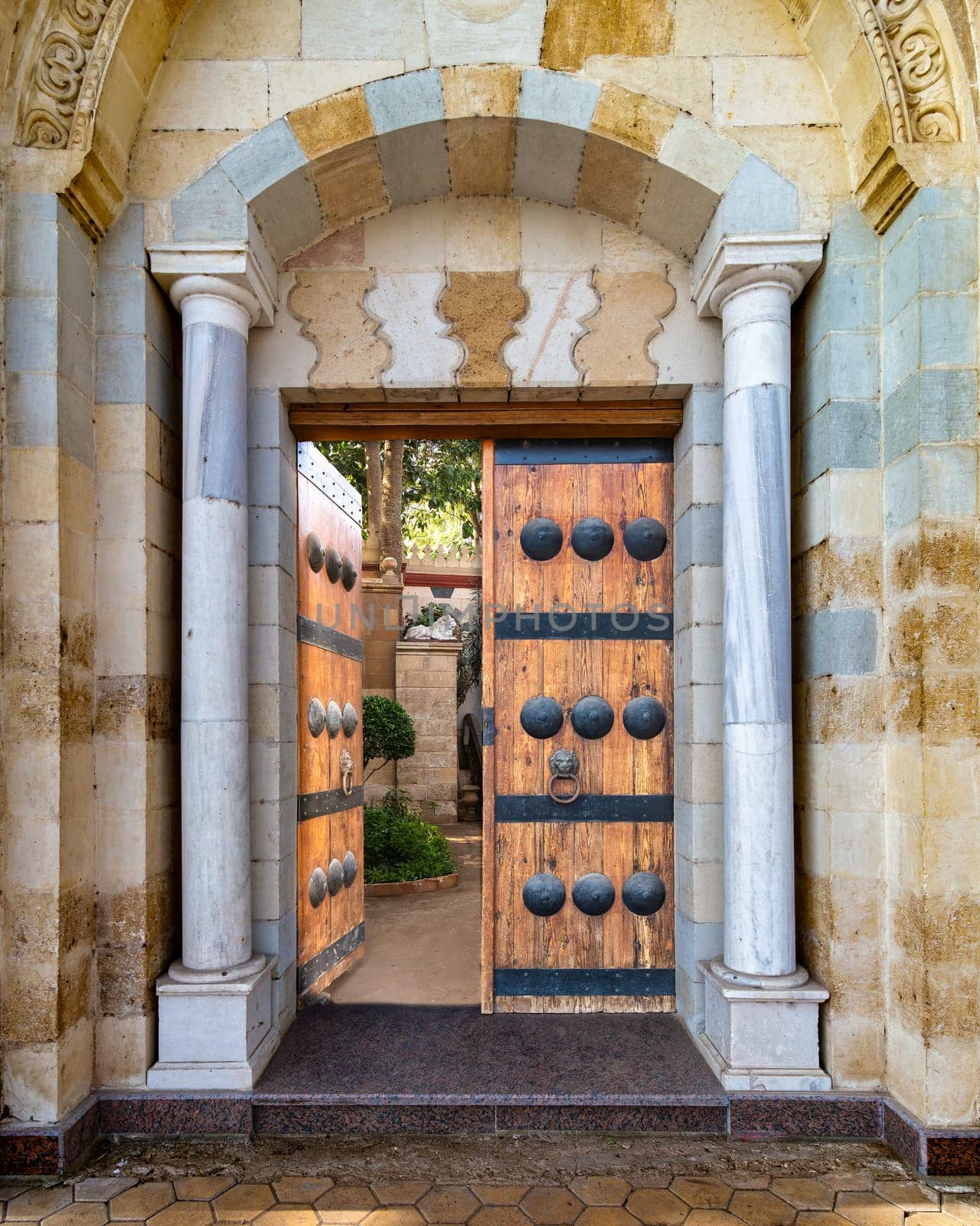 Detailed view of a intricate Mamluk style door, including dekoratif metalwork and timeworn handles. The door is leading to a shadowy passage