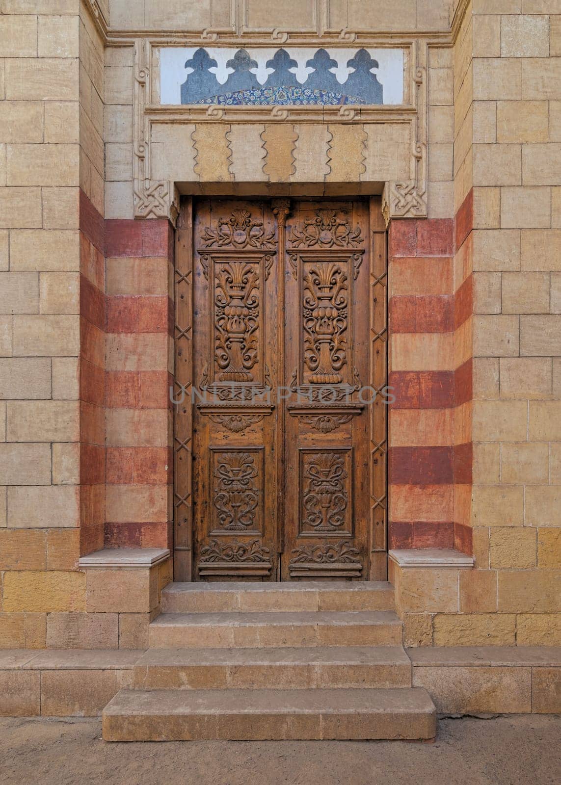 Close up view of a beautifully carved wooden door in the Mamluk architectural style. The door is adorned with intricate floral and geometric patterns and arabesque designs, typical of this Islamic art