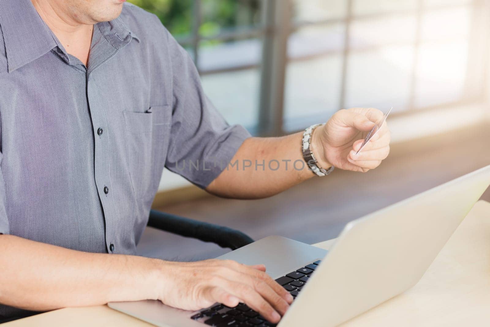 Closeup Asian senior adult man holding credit card and using technology on laptop computer, Online shopping payment with a customer network connection via an Omnichannel system