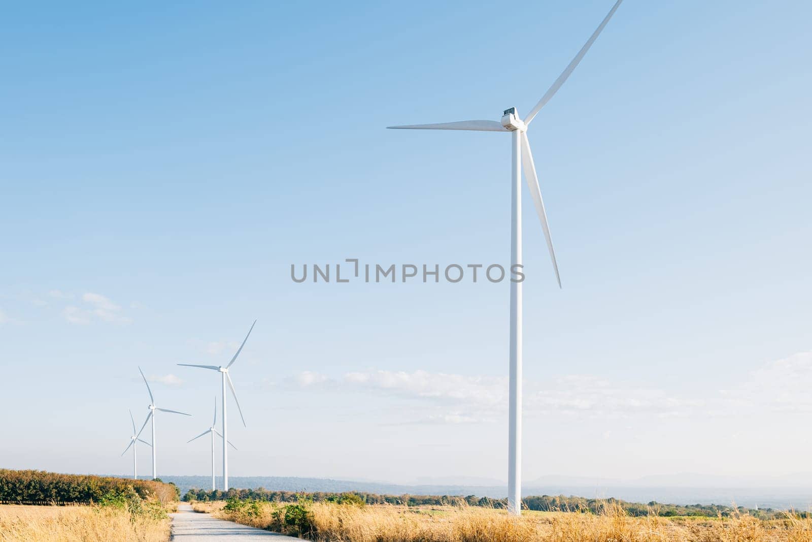 On a mountain farm windmill turbines symbolize clean energy innovation. Sustainable development thrives with modern wind technology against the backdrop of a blue sky.