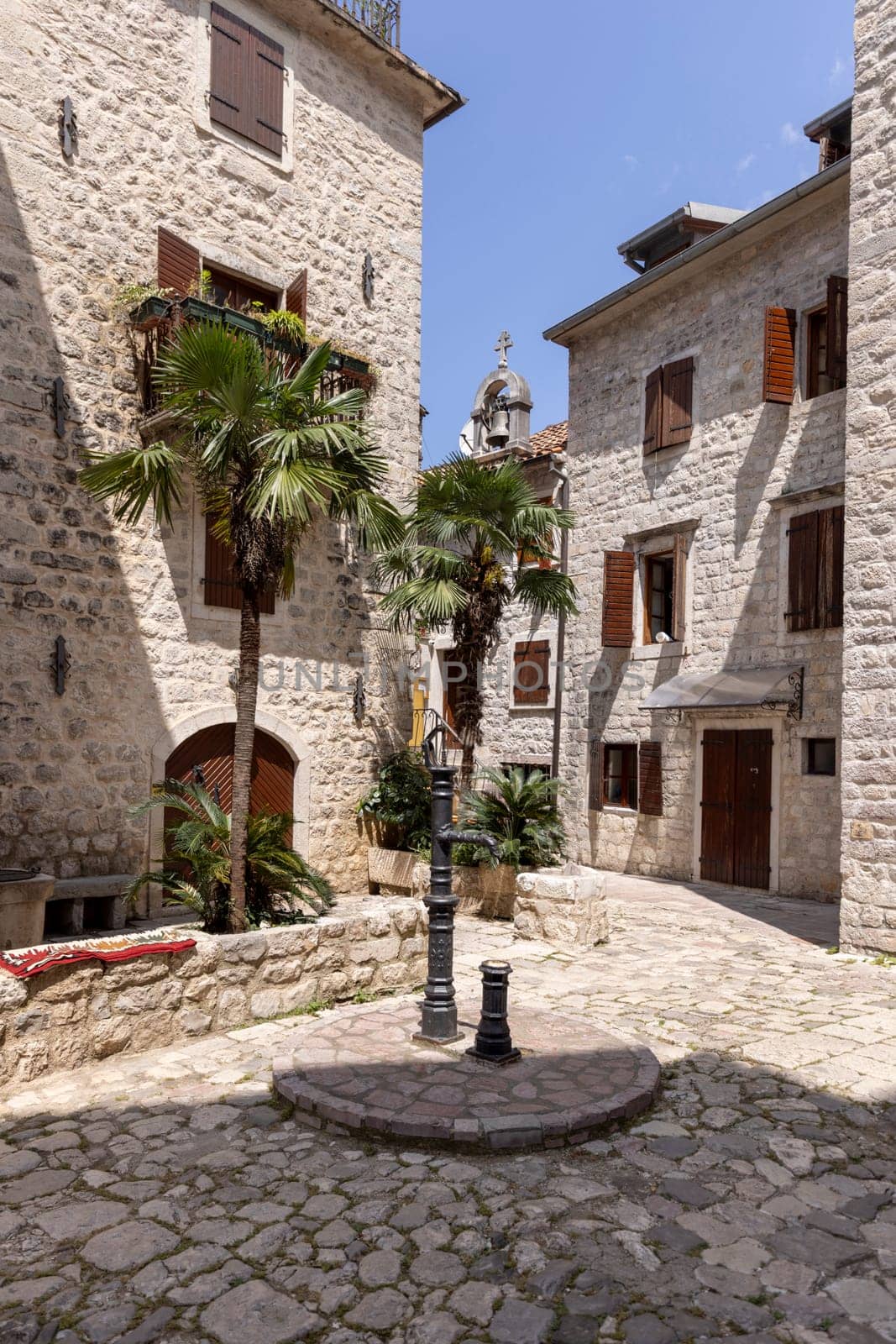 Picturesque small square in the Old Town surrounded by stone tenement houses with a metal well, Kotor, Montenegro