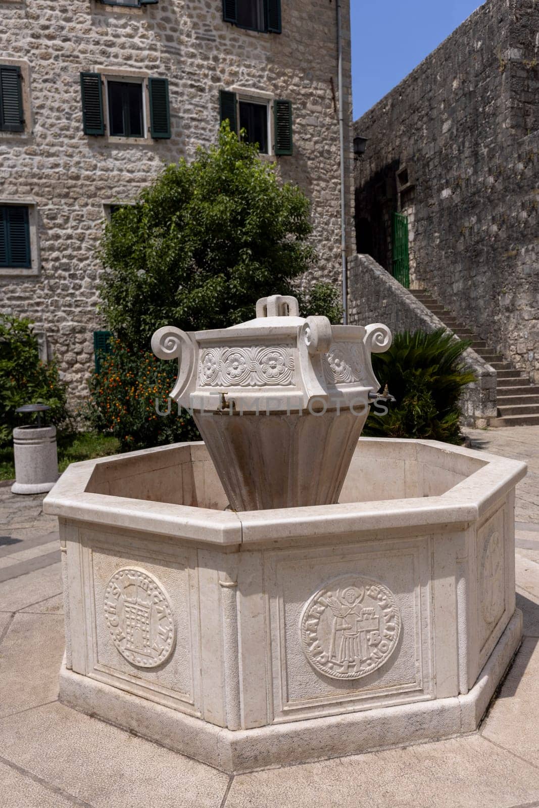 Kotor, Montenegro - June 26, 2023: View of Wood square by Old City Walls with stone decorative fountain