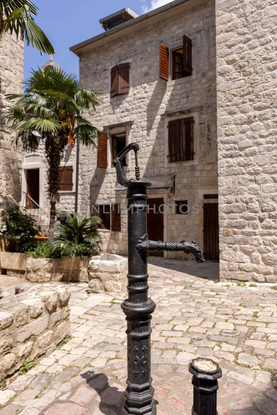Picturesque small square in the Old Town surrounded by stone tenement houses with a metal well, Kotor, Montenegro