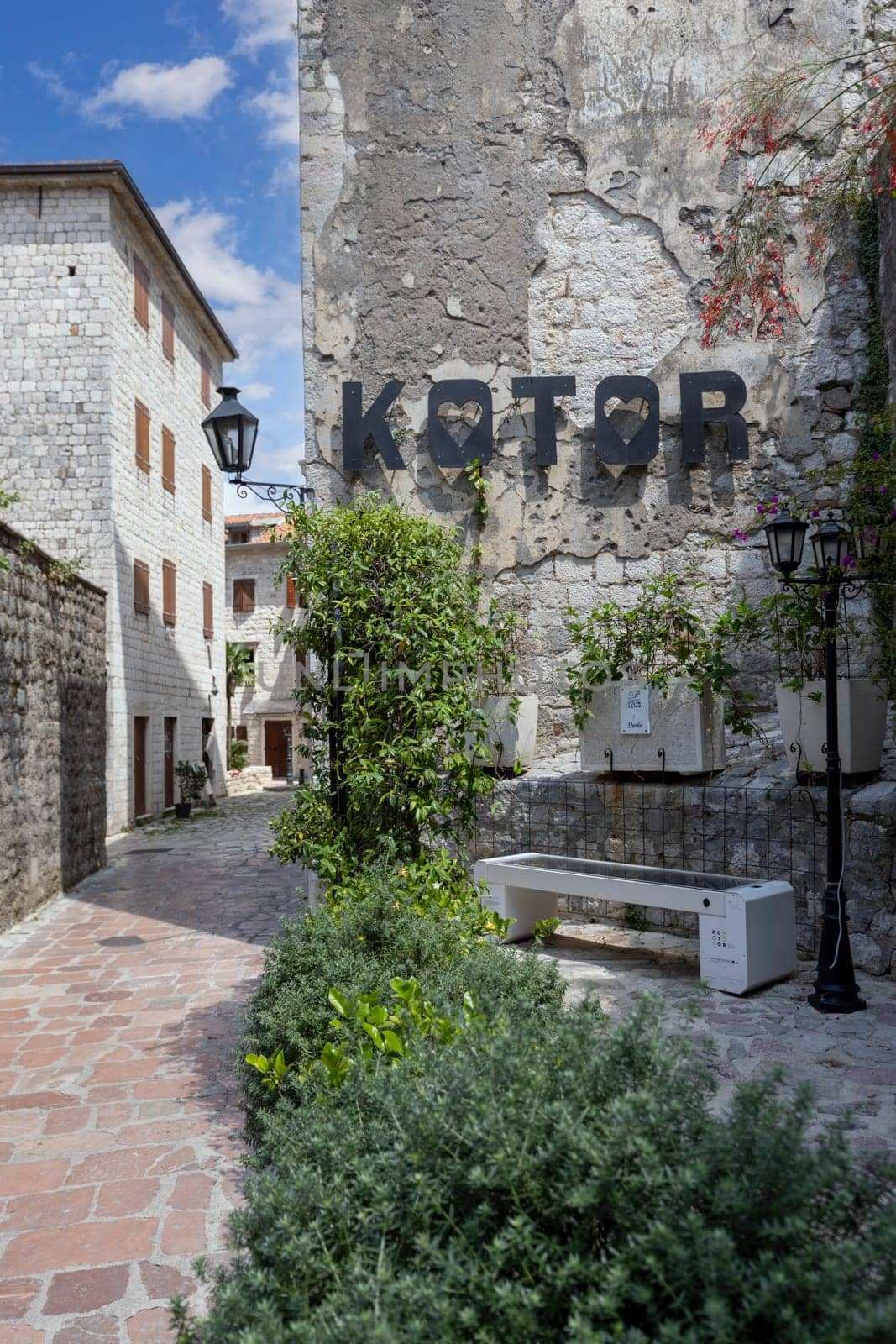 Kotor, Montenegro - June 26, 2023: Narrow street with a picturesque alley with the inscription city name Kotor on the facade of a stone tenement house