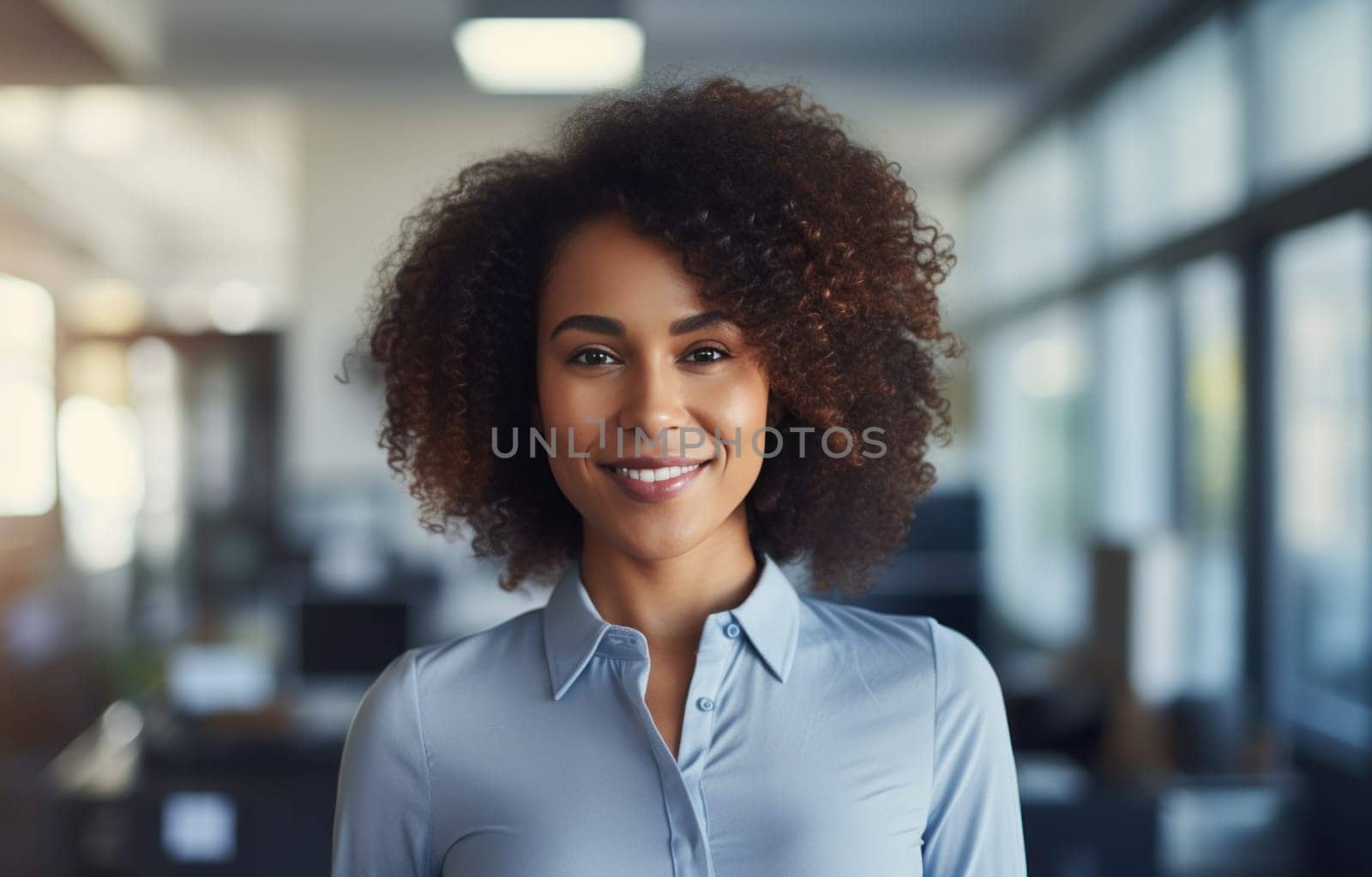 an afroamerican business woman standing in an office with a smile on her face.