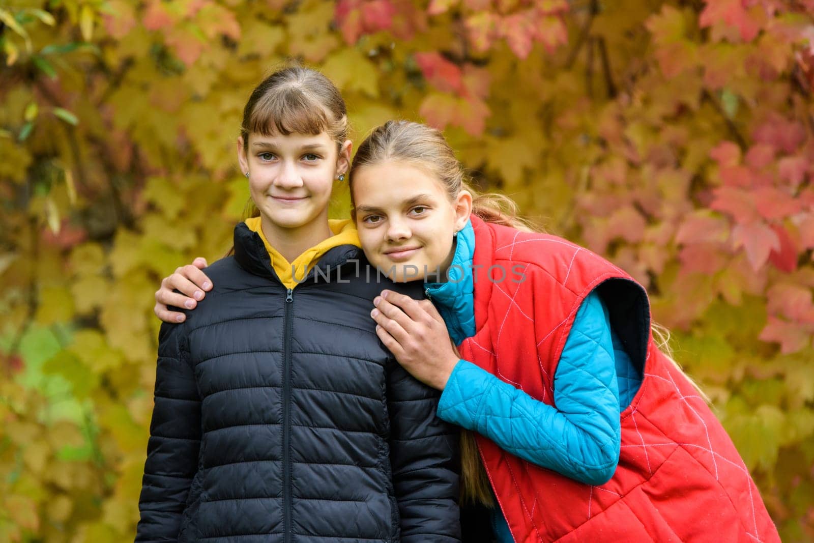 Portrait of two girls of Slavic appearance in casual autumn clothes against the background of an autumn forest