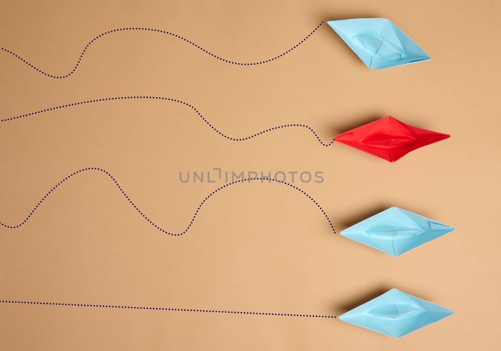 Paper boats on a brown background with paths of movement, representing the concept of individuality. Top view