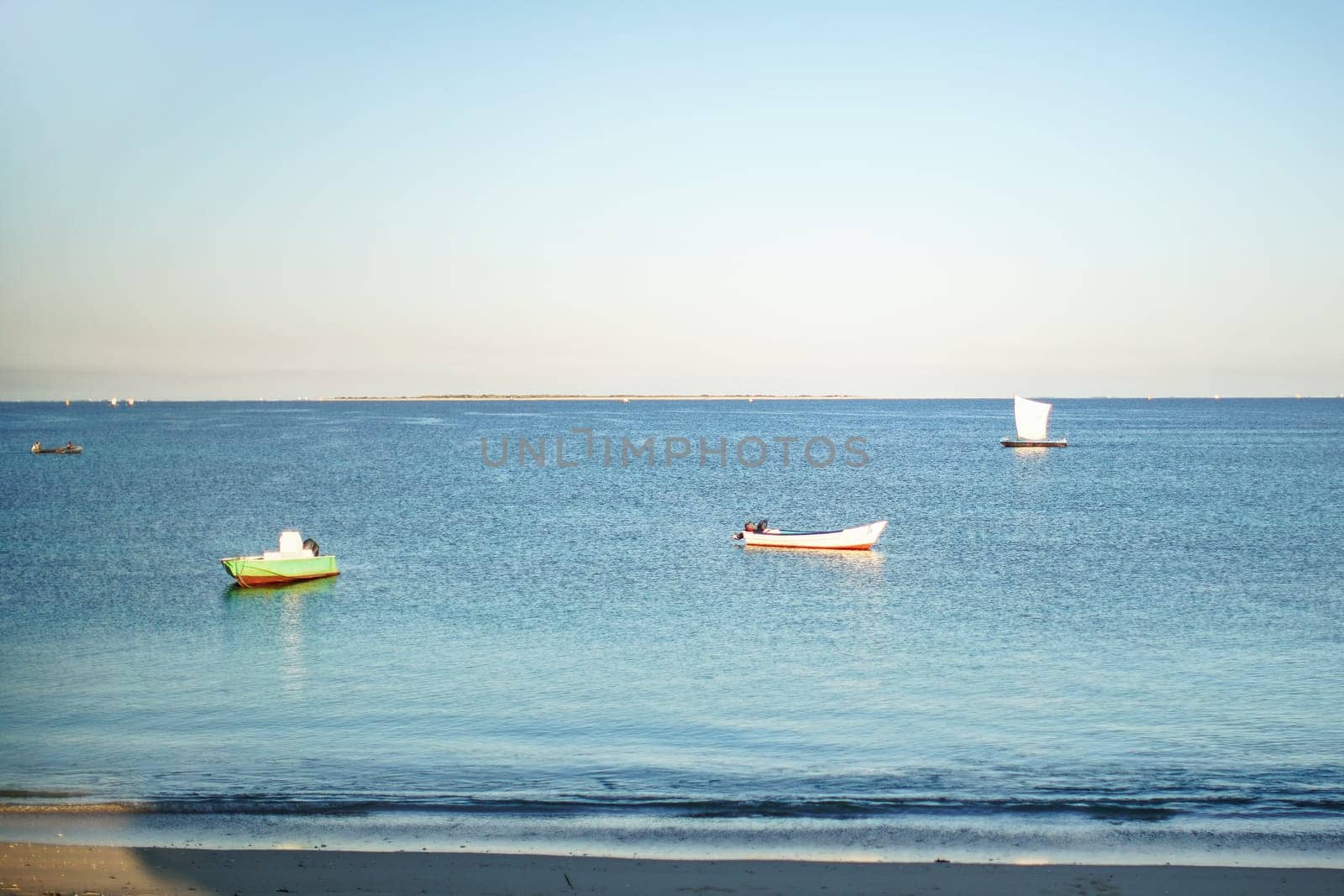 Sun shines on small fishing boats on calm sea near shore in Anakao, Madagascar