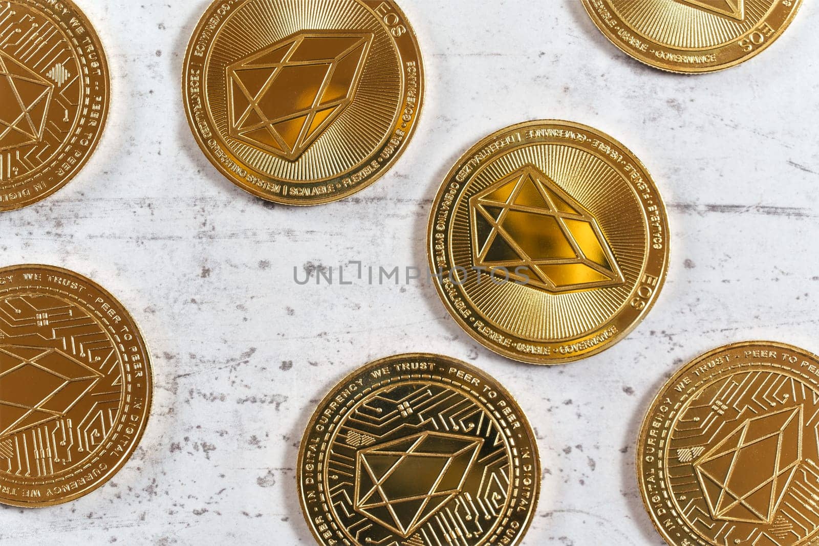 Top down detailed view, golden commemorative EOS - EOSIO  cryptocurrency - coins on white stone board