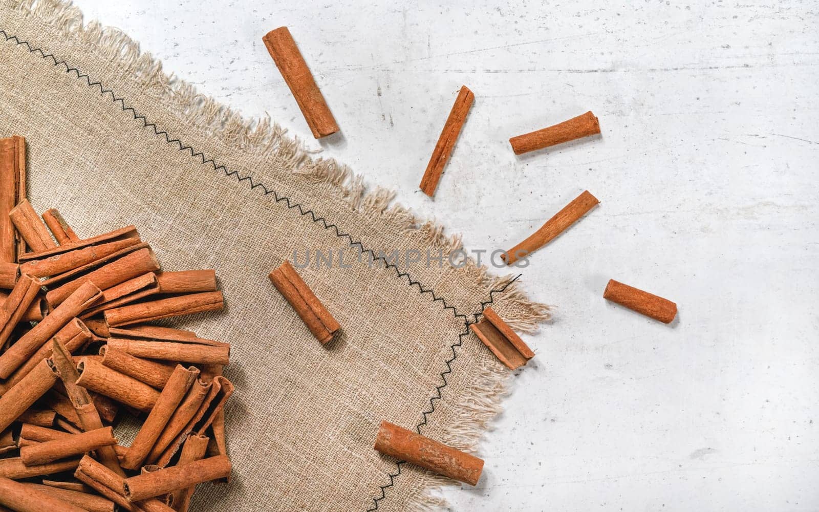Tabletop view - Heap of cinnamon bark sticks on linen tablecloth and white stone desk
