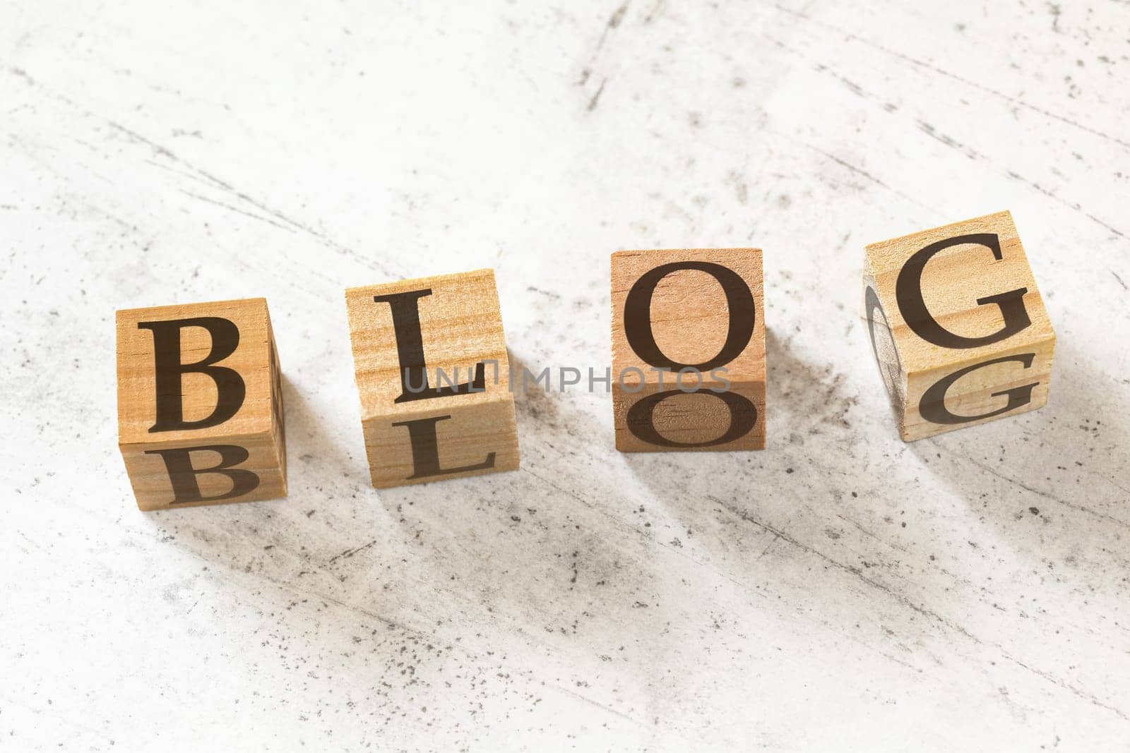 Four wooden cubes with word BLOG on white working board.