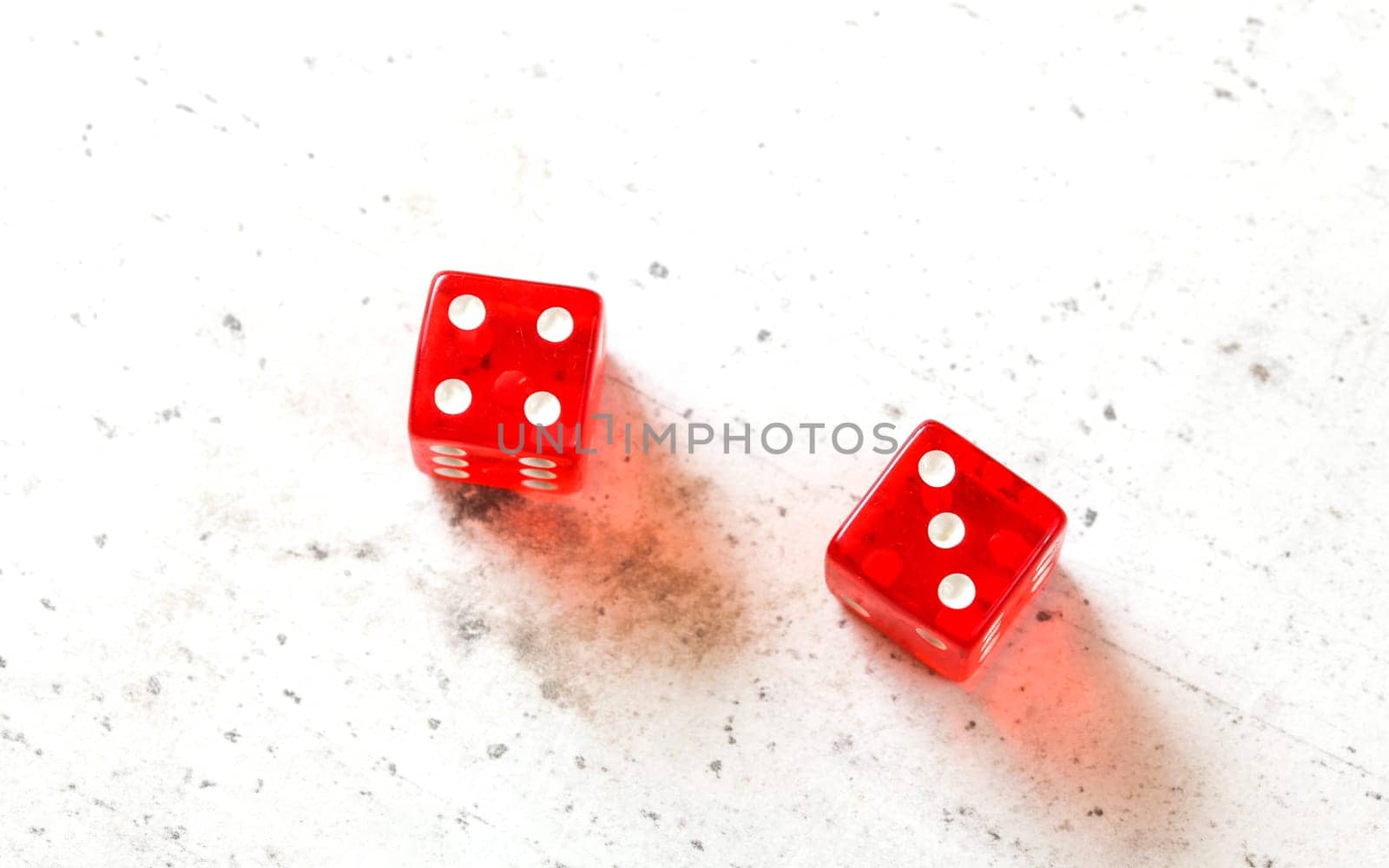 Two red craps dices showing Natural or Seven Out (number 4 and 3) overhead shot on white board
