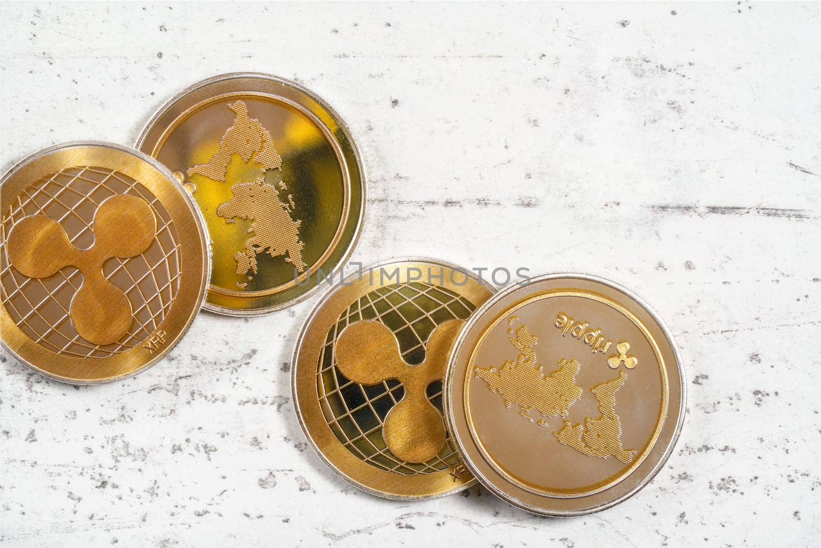 Top down view, group of golden ripple - XRP - coins on white stone board