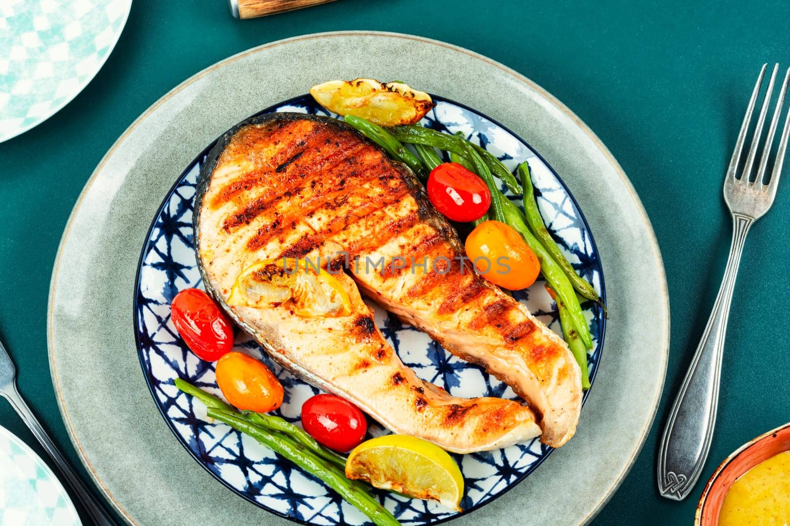 Roasted salmon garnished with potatoes and green beans. Grilled fish.