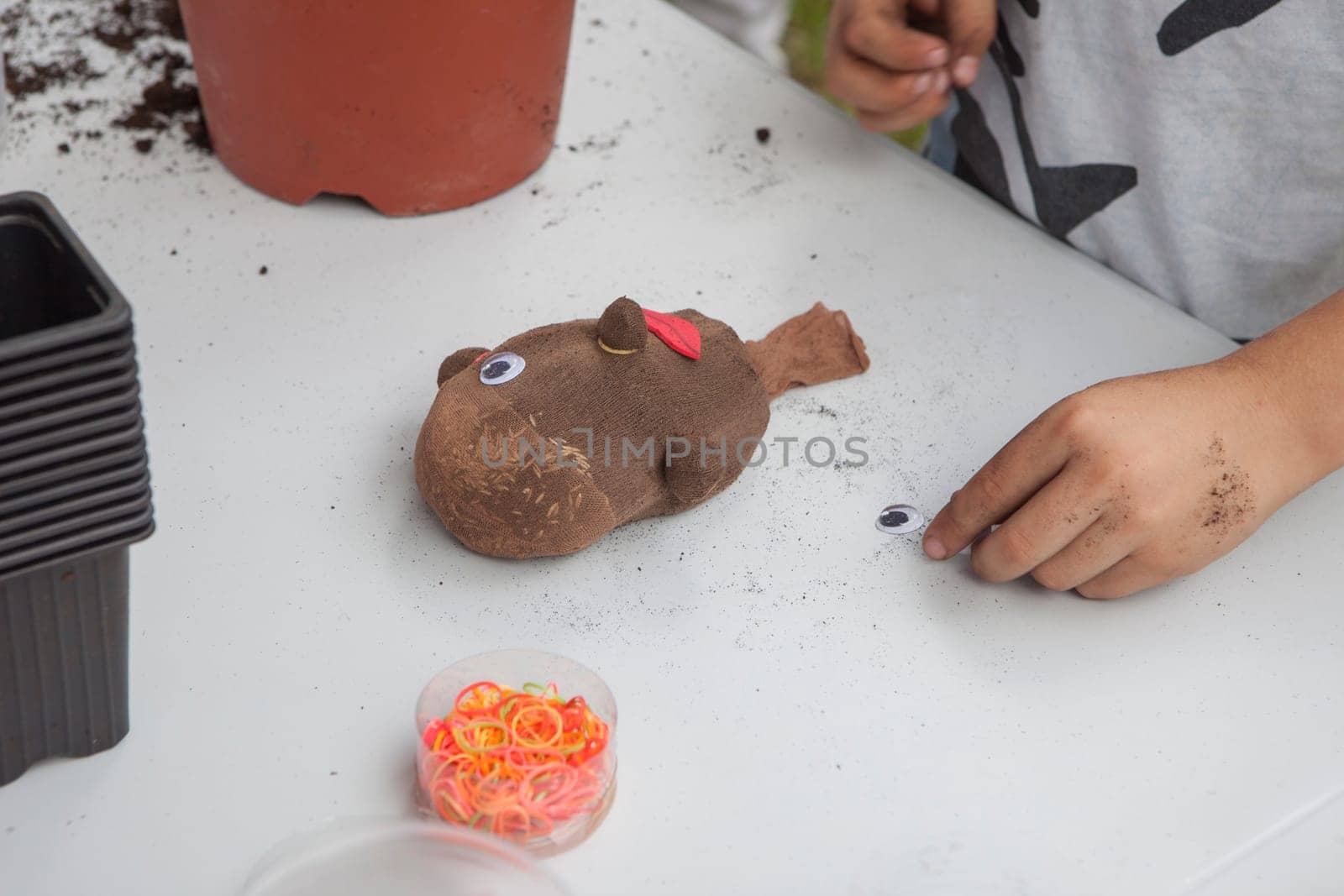 Grass heads workshop for children. Kid placing googly doll eye