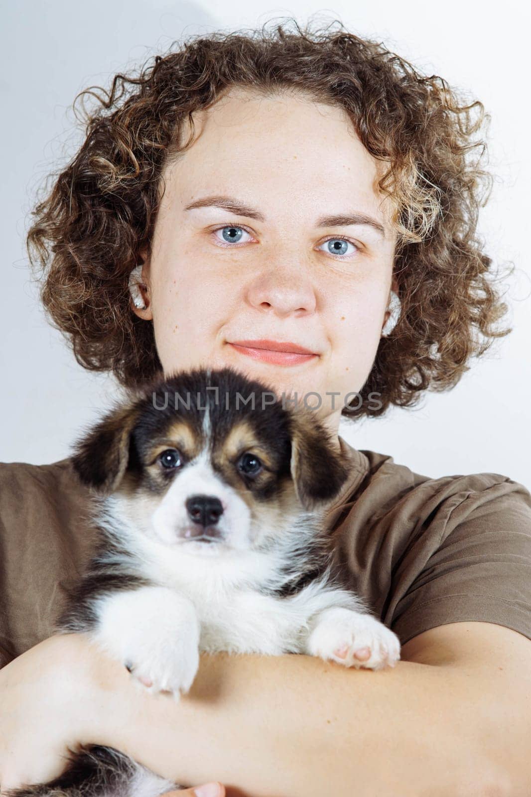 Close-up portrait of face of charming woman, owner of small Welsh corgi puppy, whom she holds in her arms. Dog food. Pets. Dog in family. Features of keeping puppies. Veterinary control. Loyal friend.