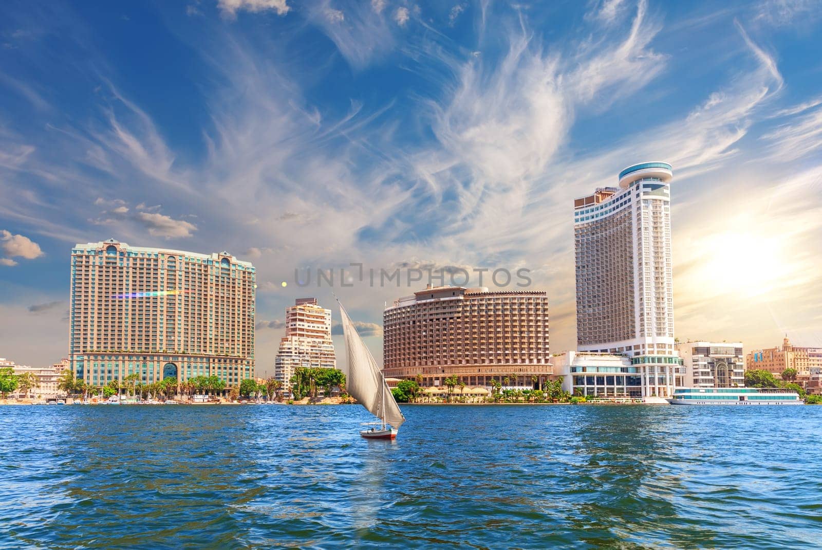Nile river with a boat by the luxurious buildings of modern Cairo, Egypt.