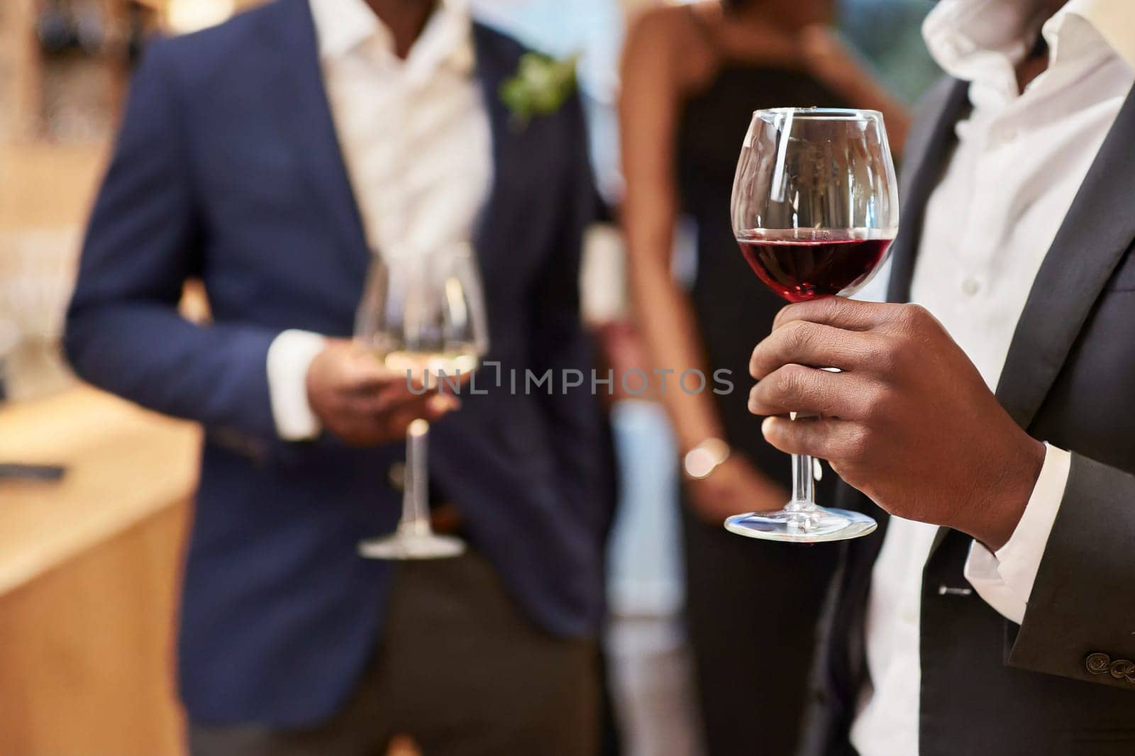 Businessman holding a glass of red wine in the office with colleagues in the background. AI generated