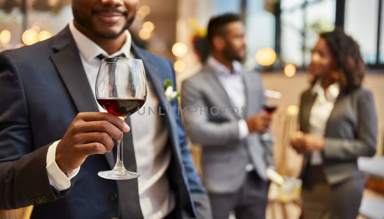 Businessman holding a glass of red wine in the office with colleagues in the background. AI generated