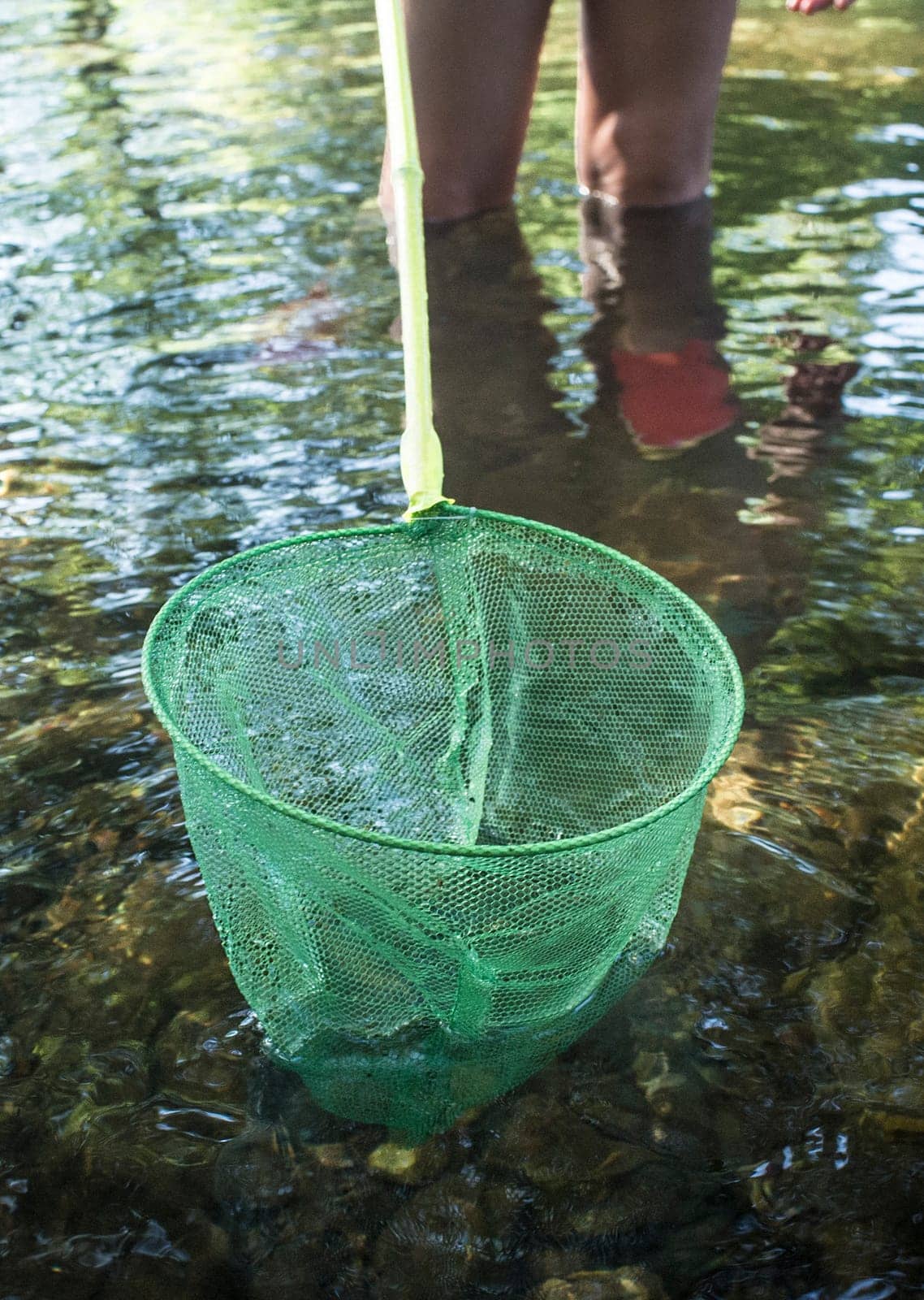 Little girl playing with fishing net in the river. Holidays where kids can go wild concept