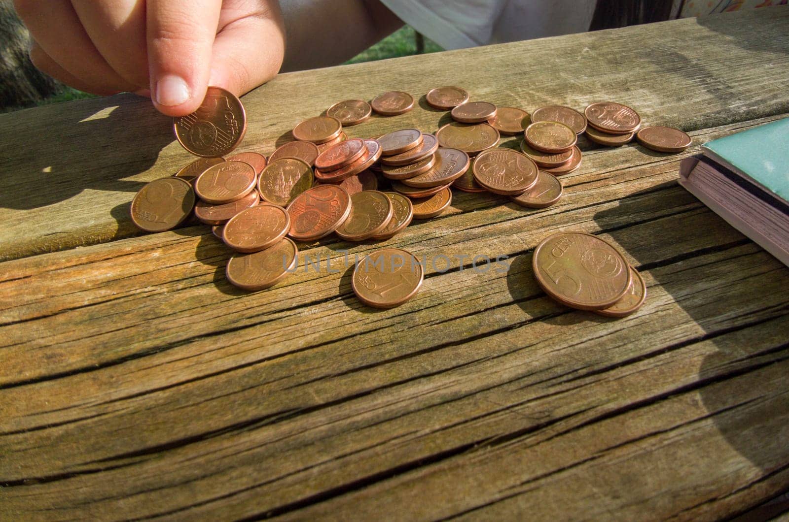 Little girl counting her pocket change savings. Weathered picnic table as background