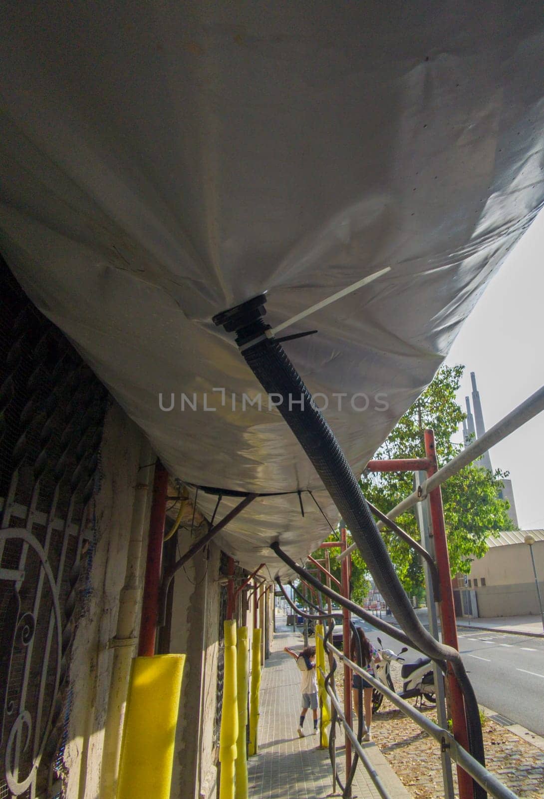 Scaffold equipped with pedestrian protection devices. Dust collection tubes. Ground level