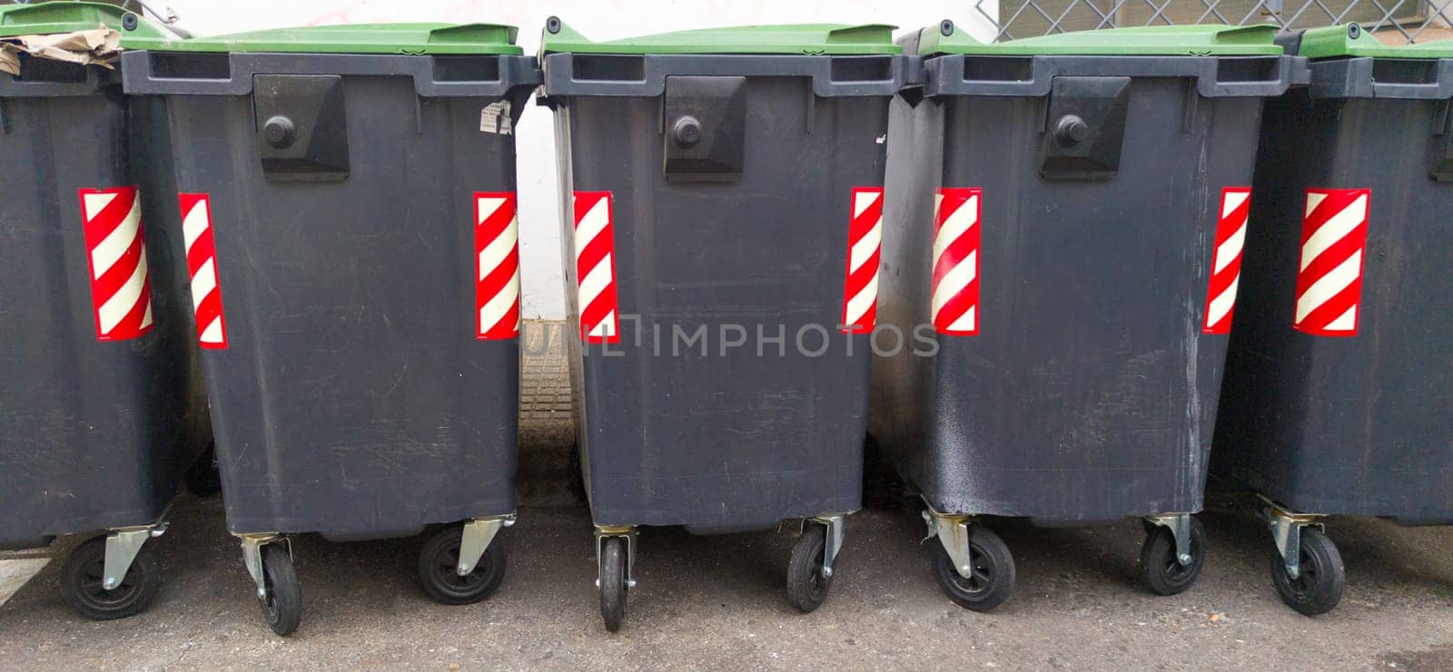 Line of grey dumpsters on sideway. Long format view