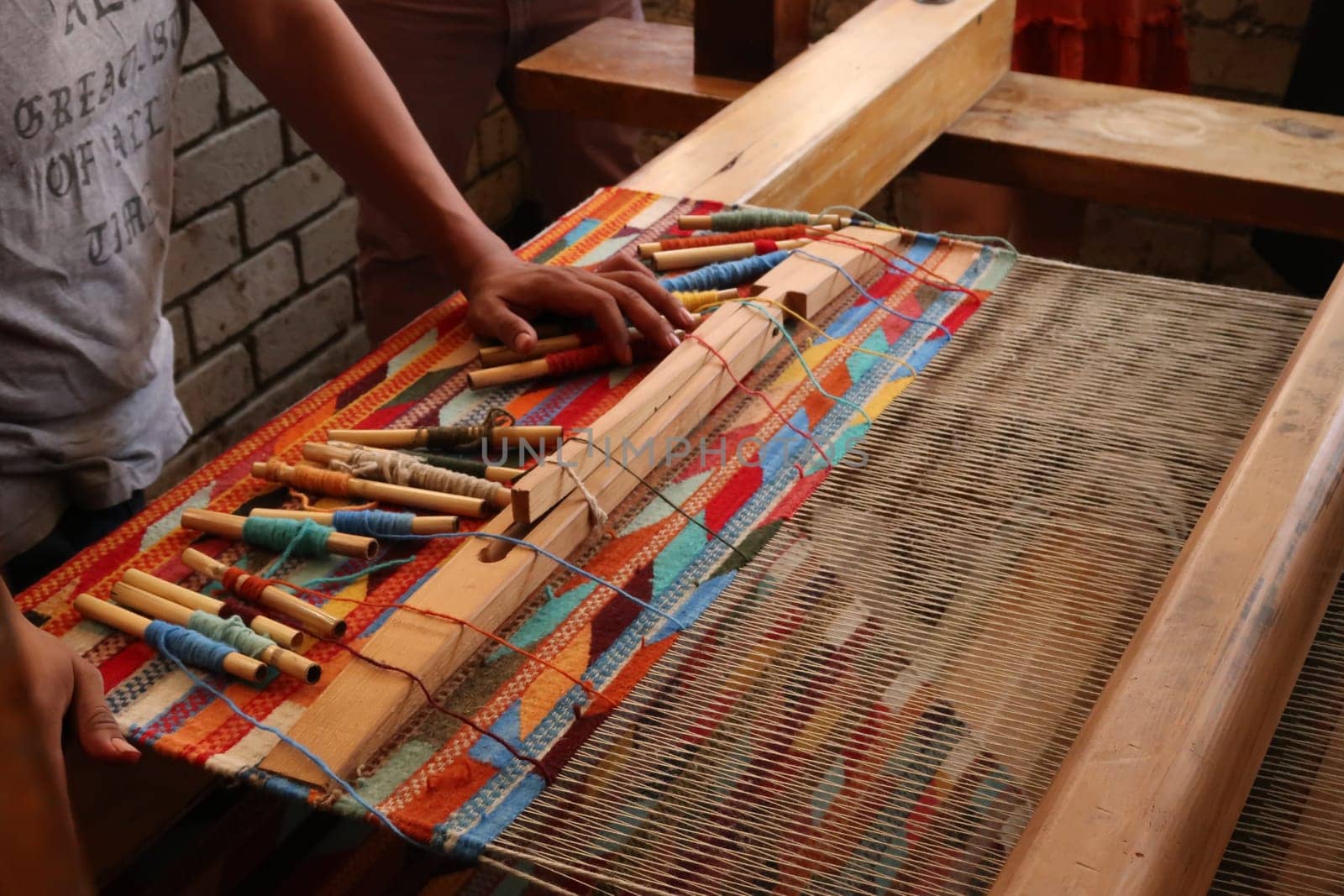 Man in a workshop standing next to a traditional loom, about to weave a colorful carpet, Oaxaca, Mexico 2022