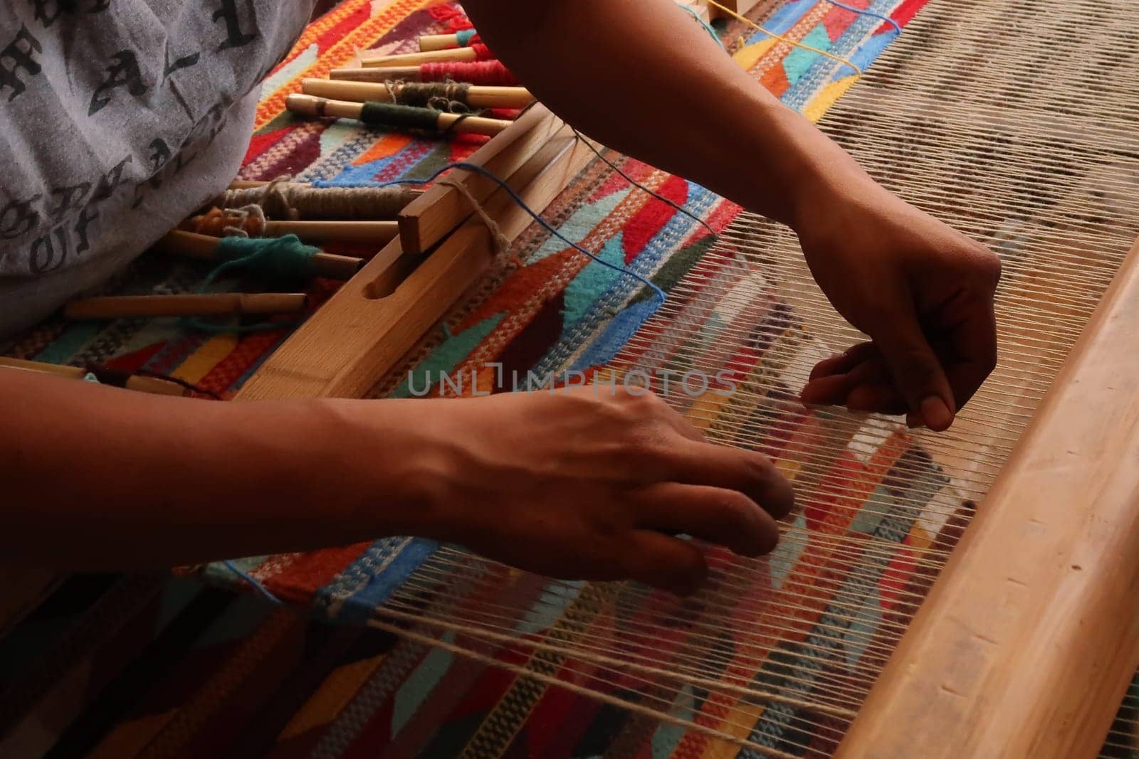 Man in a workshop weaving a colorful carpet on a traditional loom, Oaxaca, Mexico 2022