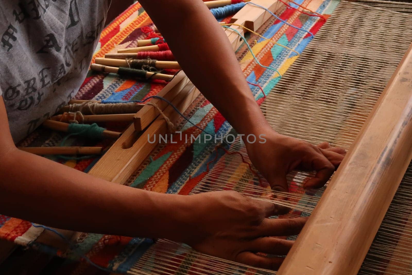 Man in a traditional workshop weaving a colorful carpet on a loom, Oaxaca, Mexico 2022
