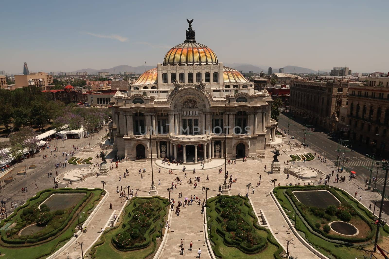 The beautiful Palacio de Bellas Artes/Palace of Fine Arts and the square and flower beds in front of it on a busy day, Mexico City 2022