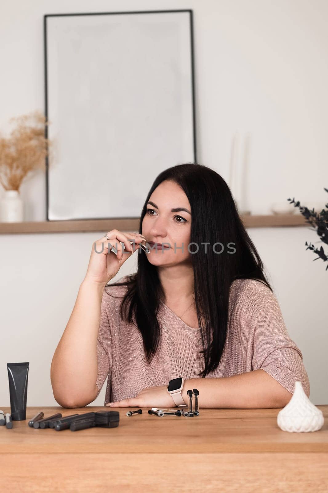 A brunette girl sitting at a desk in the office sniffs small perfume samples in close-up