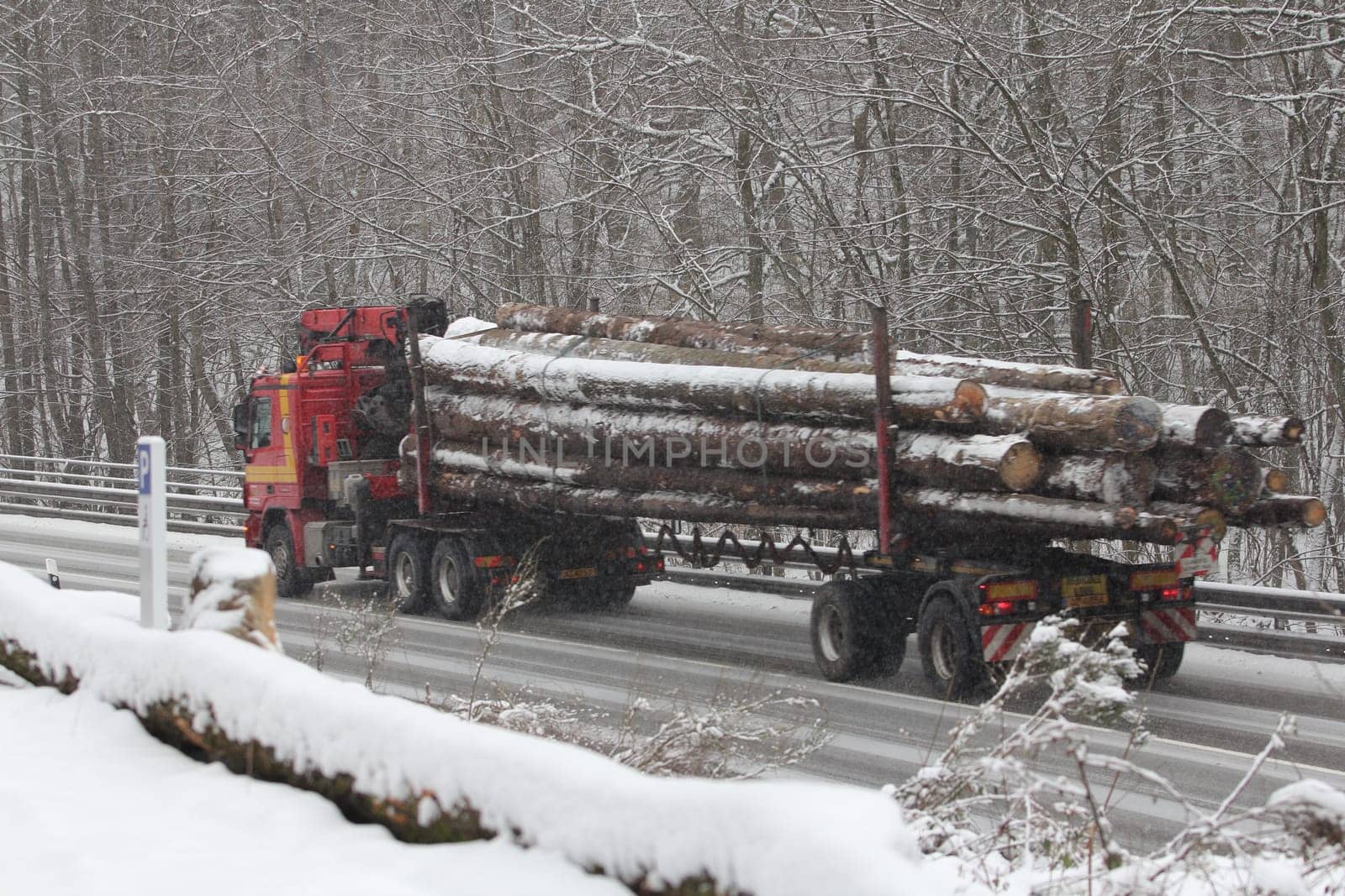Birkenfeld, Germany February 6, 2018: A truck loaded with logs drives on a wintry road
