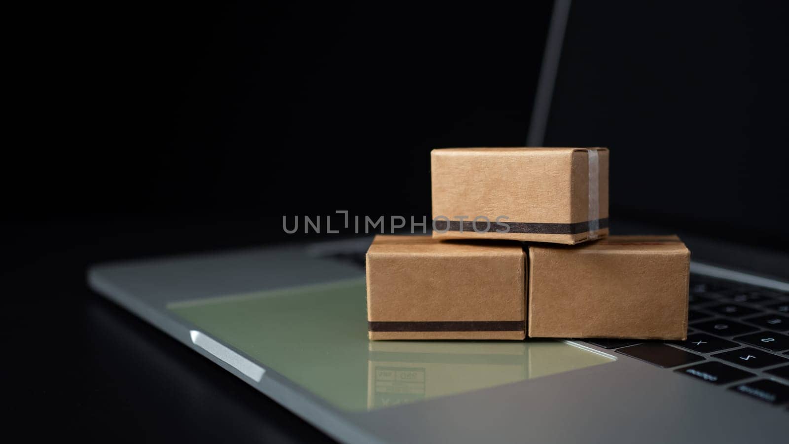 Boxes on a laptop keyboard on dark background. Ideas about online shopping, online shopping is a form of electronic commerce that allows consumers to directly buy goods from seller over the internet.