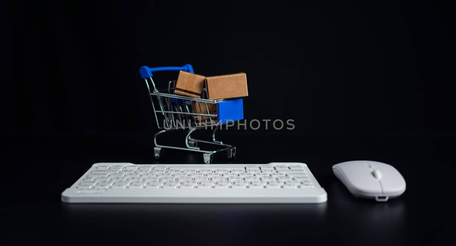 Boxes in a shopping car and keyboard on dark background. Ideas about online shopping, Online shopping for electronic commerce, Allows consumers to directly buy goods from seller over the internet.