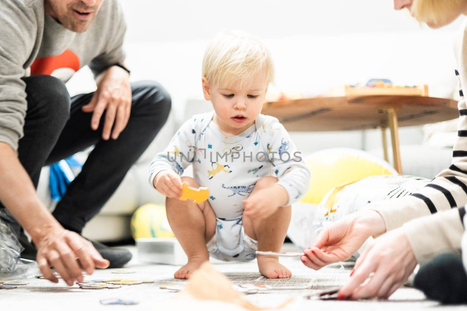 Parents playing games with child. Little toddler doing puzzle. Infant baby boy learns to solve problems and develops cognitive skills. Child development concept.