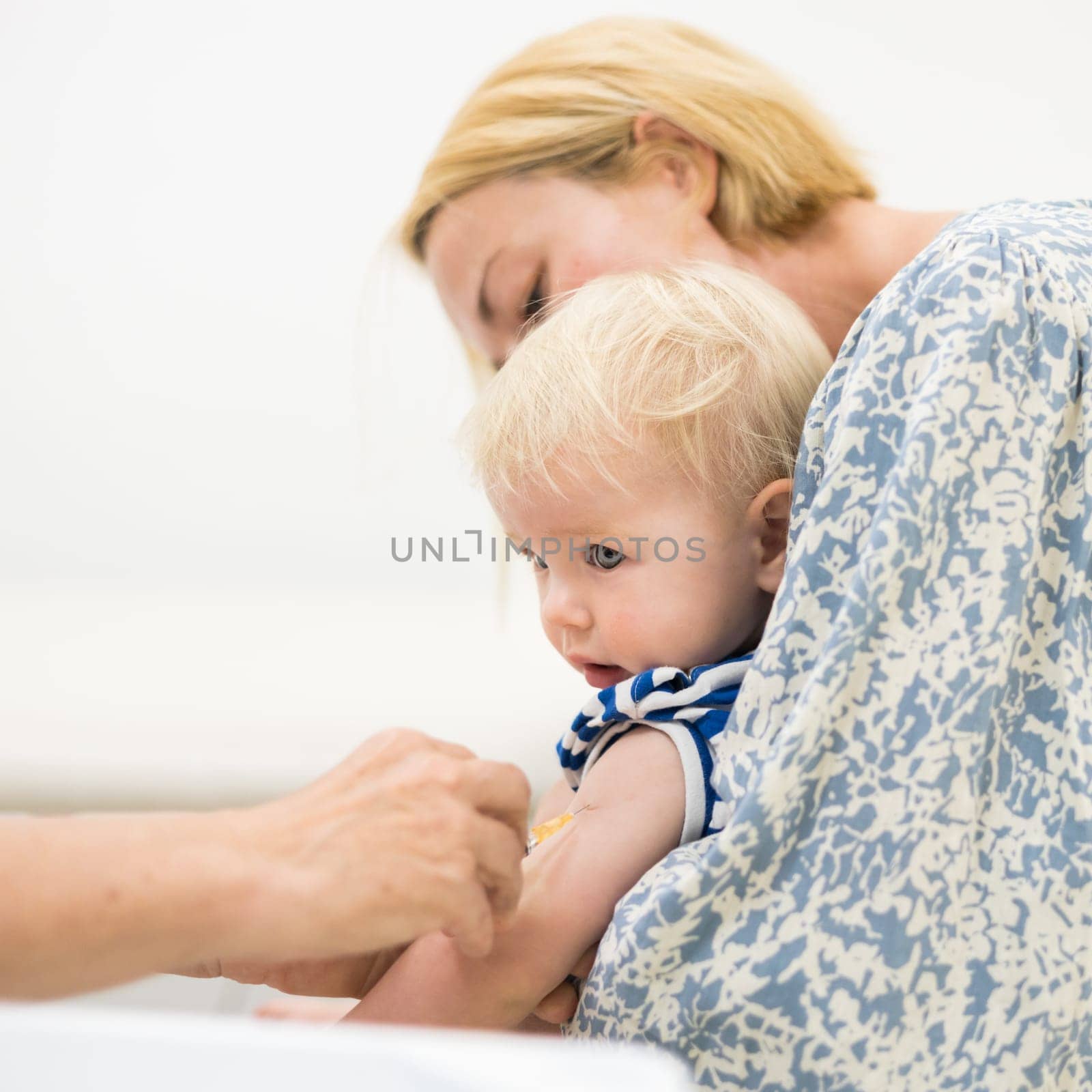 child beeing vaccinated by pediatrician in presence of his mother. Preventive vaccination against Diphtheria, whooping cough, tetanus, hepatitis, haemophilus influenzae, pneumococcus, poliomyelitis.