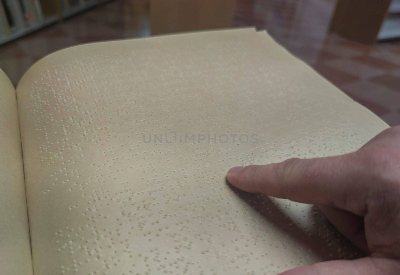Blind male reading braille language book at library. Selective focus