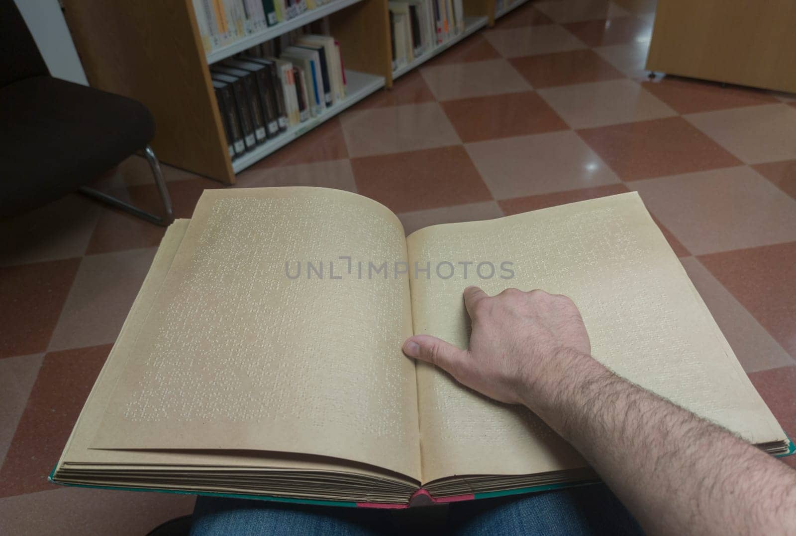 Blind male reading braille language book at library. Point of view shot