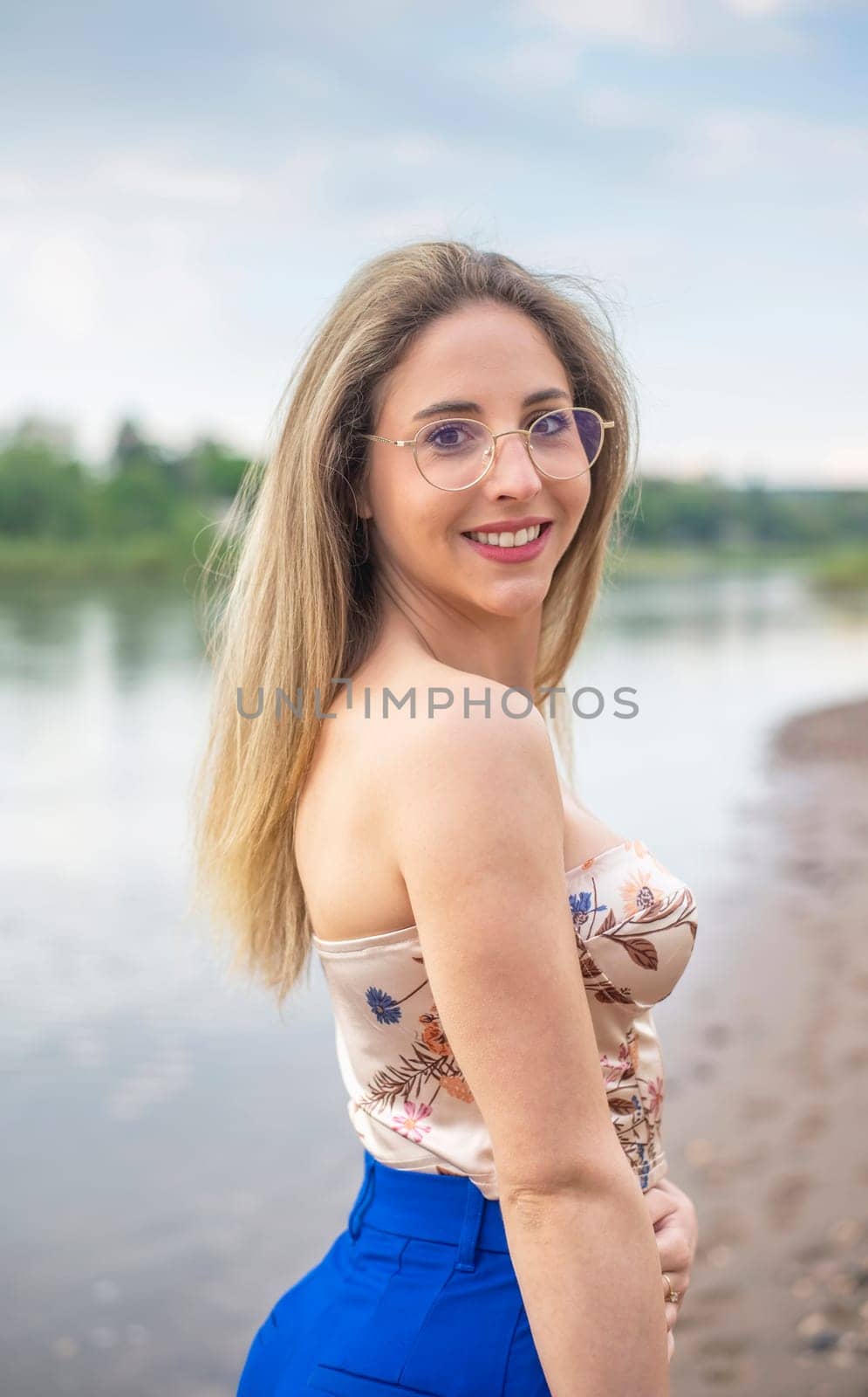 young woman with glasses standing on riverbank