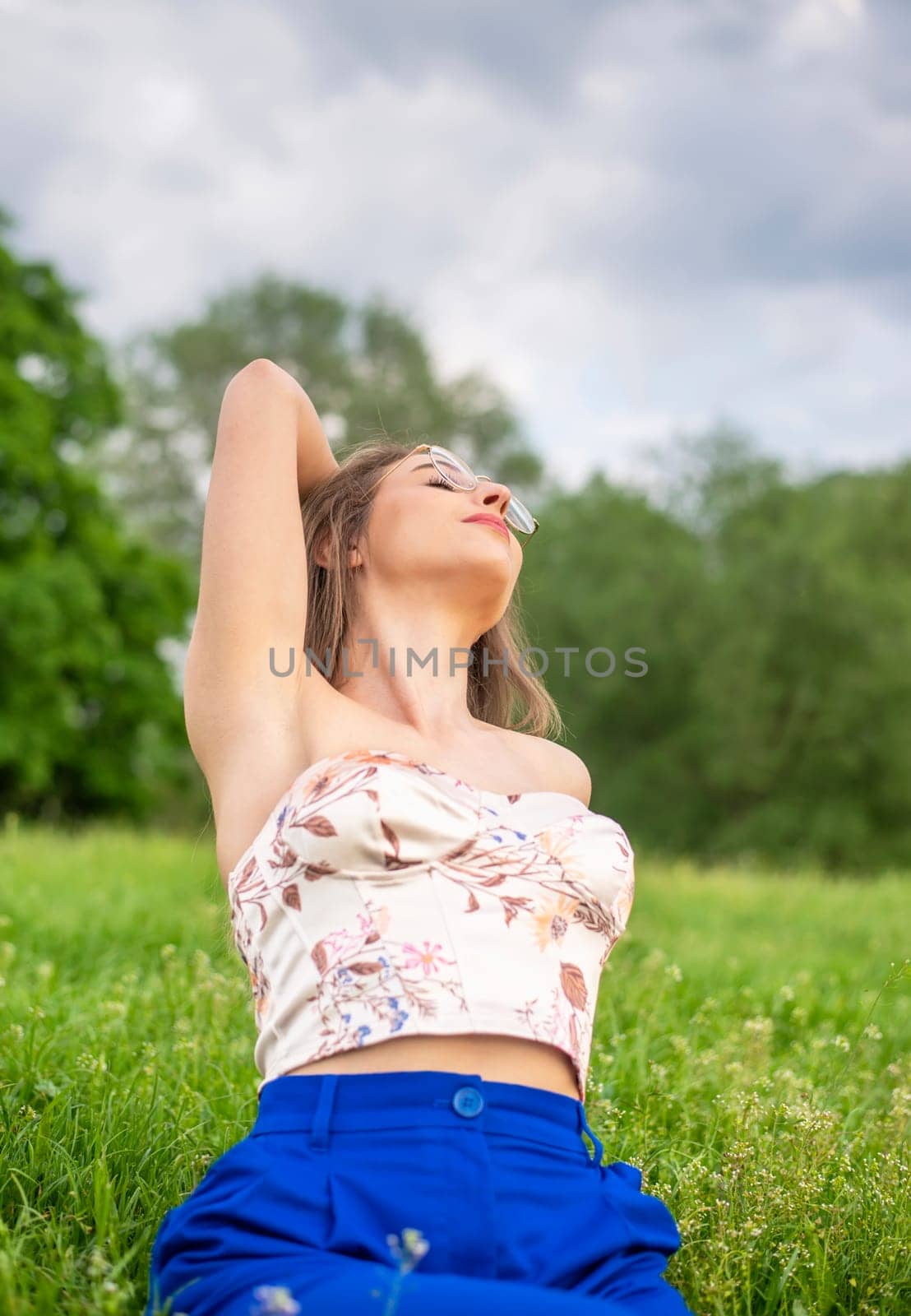 young woman with glasses sitting on a meadow