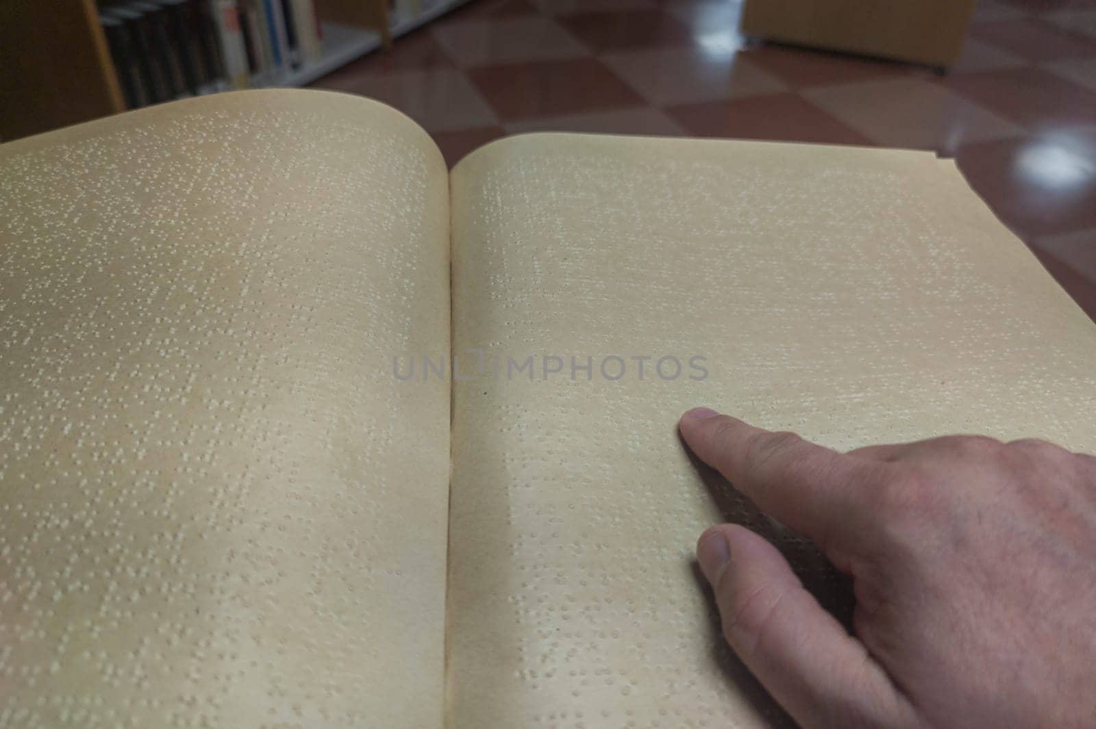 Blind male reading braille language book at library. Selective focus