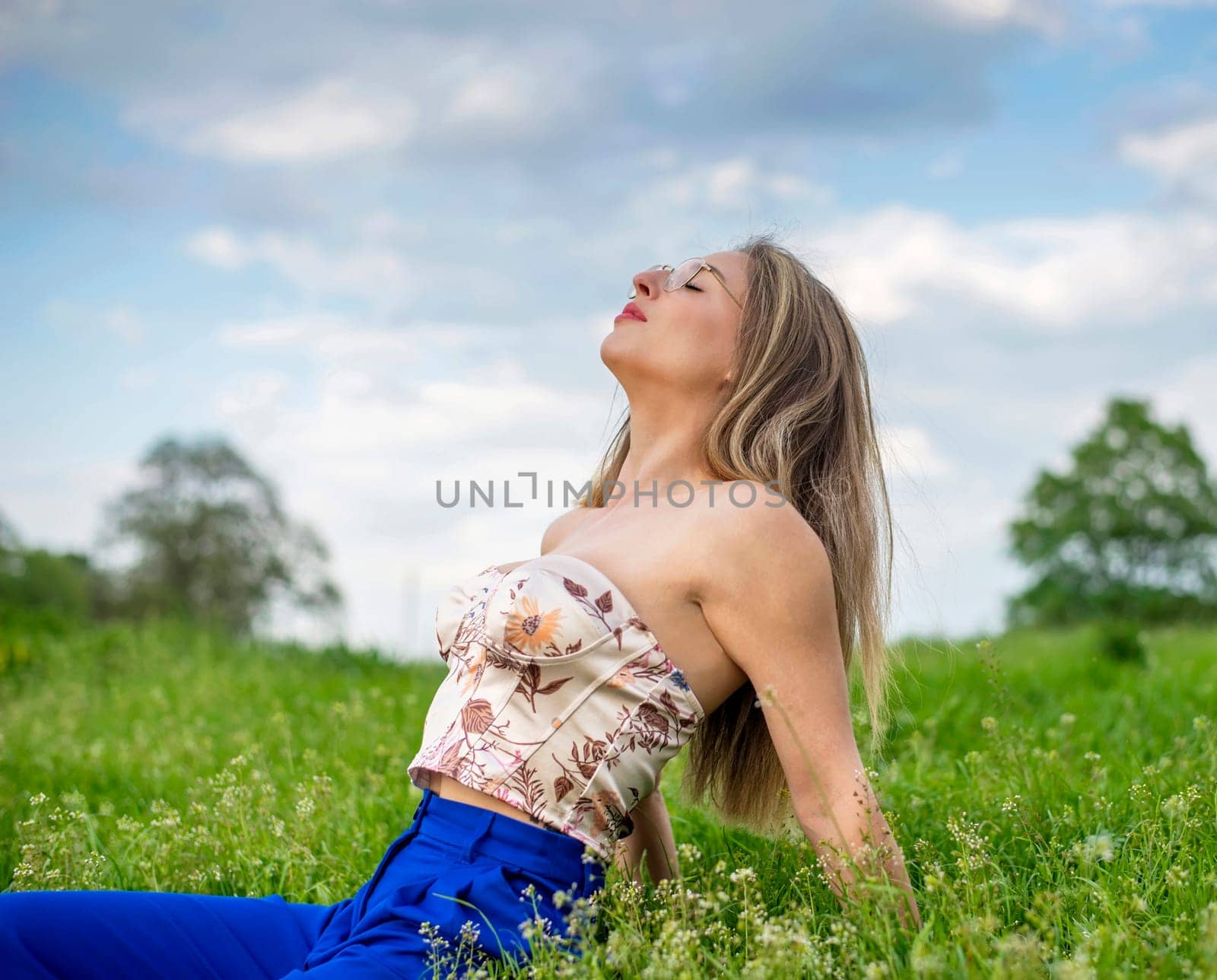 young woman with glasses sitting on a meadow