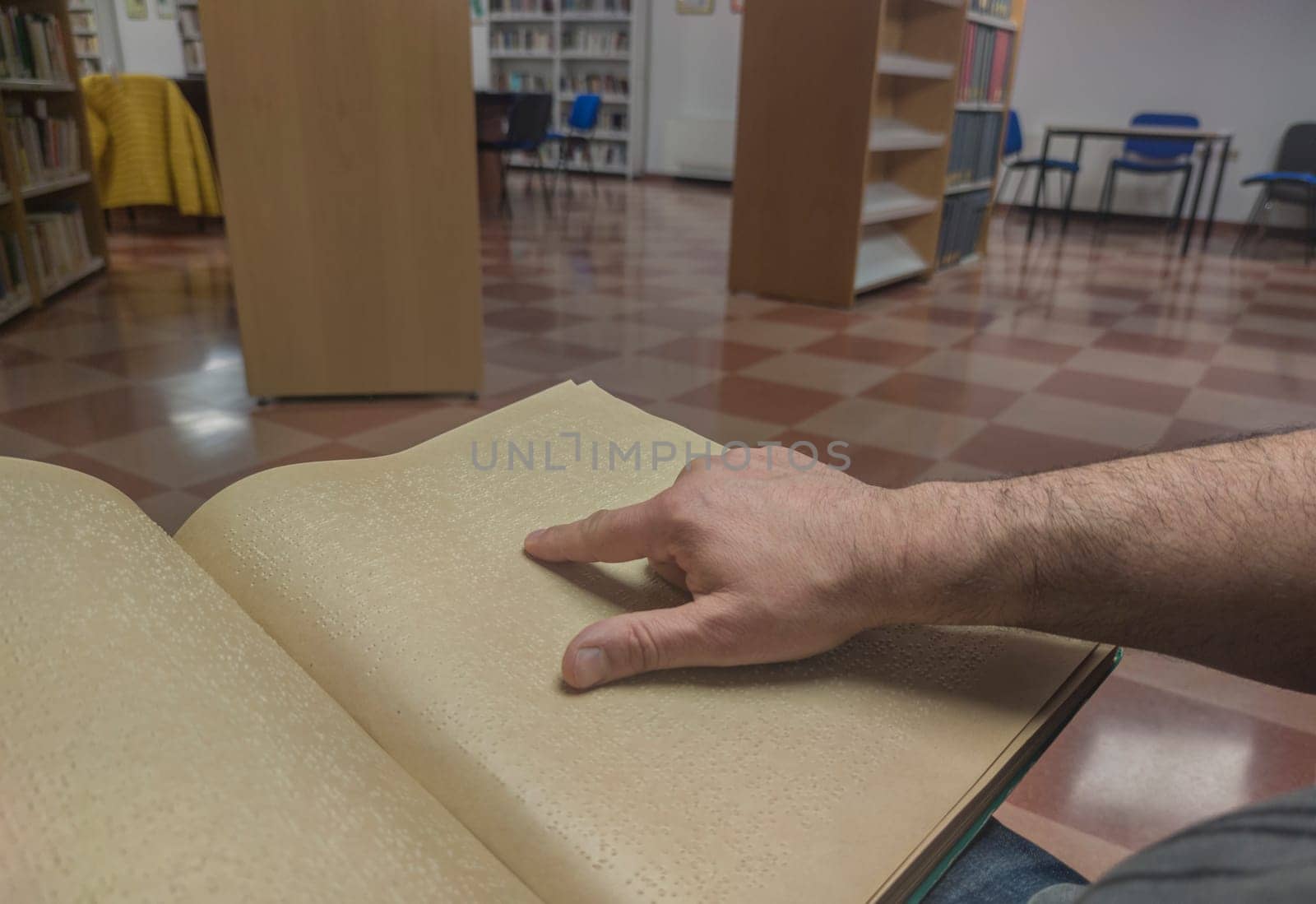 Blind male reading braille language book at library. Point of view shot