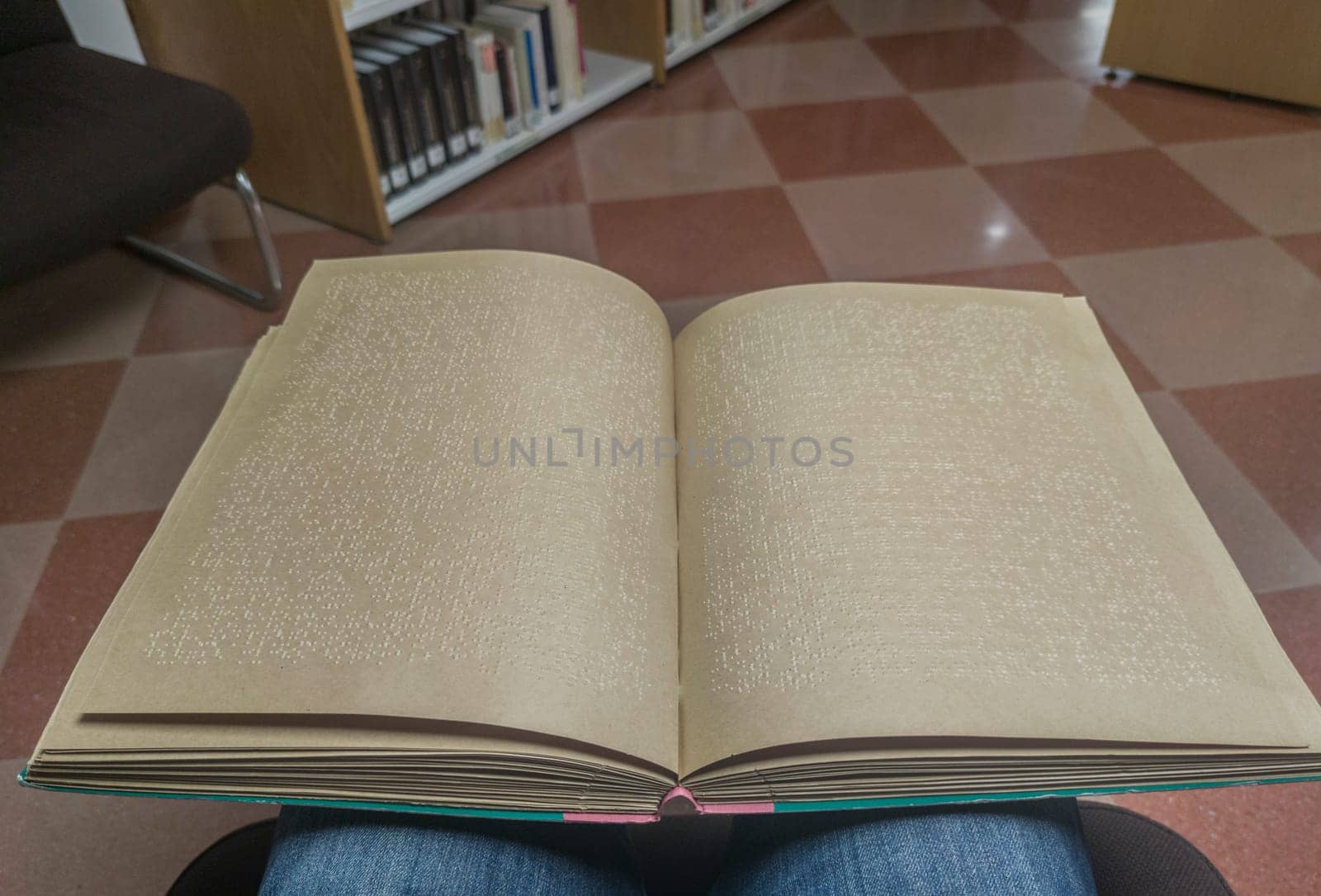 Blind male reading braille language book at library. Point of view shot